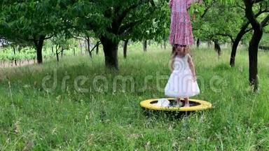 一个可爱的女孩在自然花园里跳舞。 小女孩在一个小蹦床上跳舞和跳跃。 小女孩穿白色衣服